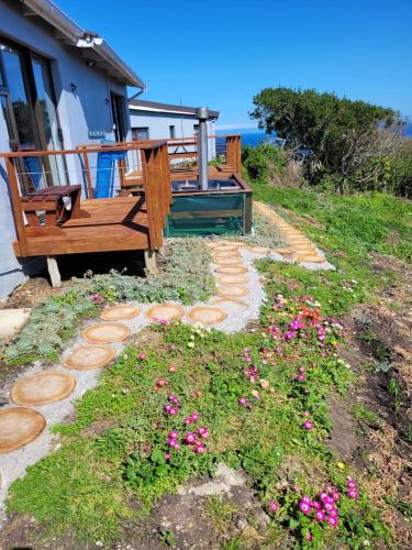 a garden with a bench and flowers in front of a house at Dolly@Skuitbaai in Eersterivierstrand