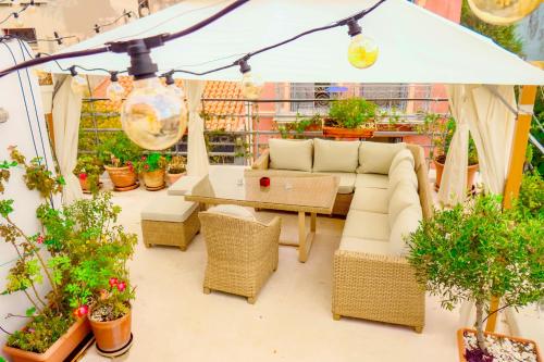 a patio with a couch and tables and potted plants at The Acropolis House of Flowers~Private Roof Garden in Athens