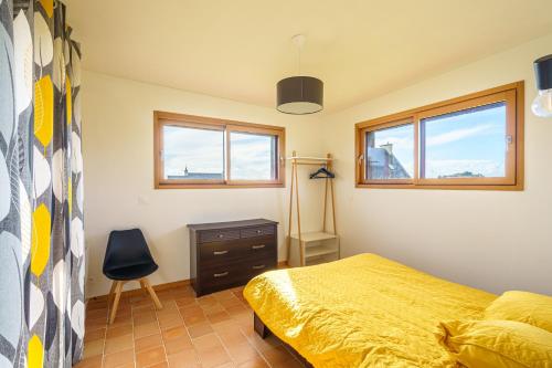 a bedroom with a bed and a desk and two windows at Ty Jane Dour - Maison avec jardin in Plouhinec