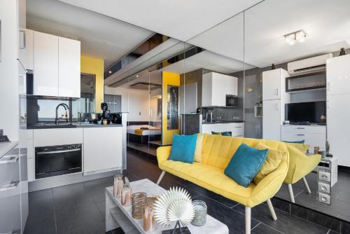 un salon avec un canapé jaune et une cuisine dans l'établissement Village Naturiste R4N - Le Mirror Port Nature Luxe, au Cap d'Agde