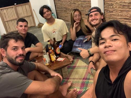 a group of people sitting around a table with beer at Jaydy hostel in General Luna