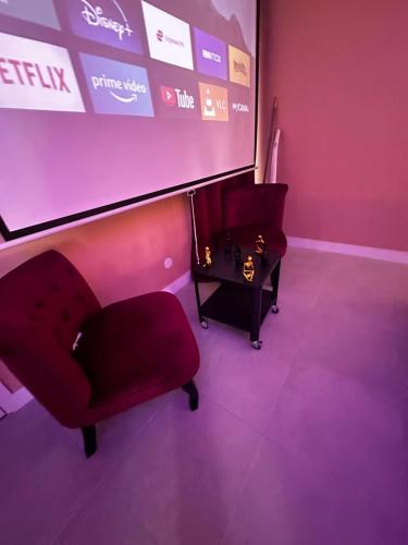 a room with a projection screen and a red chair at Crownn - Spa Privatif in Fontenay-sous-Bois