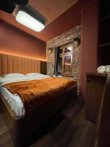 um quarto com uma cama e uma parede de tijolos em New Soho Hotel em Prizren