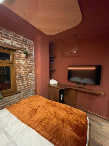 um quarto com uma cama e uma televisão de ecrã plano em New Soho Hotel em Prizren