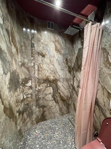 e bagno con parete in pietra e doccia. di New Soho Hotel a Prizren
