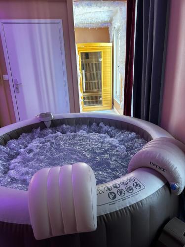 a purple bath tub with a remote control in it at Crownn - Spa Privatif in Fontenay-sous-Bois