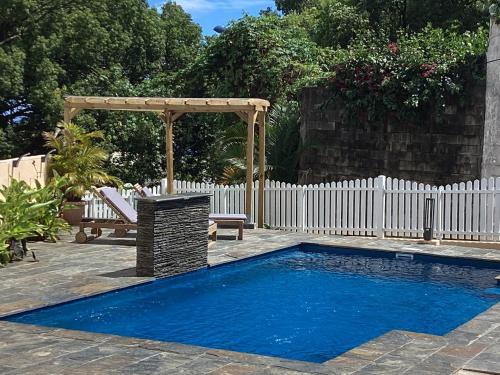 a swimming pool in a backyard with a white fence and a bench at Kaz Passion in Sainte-Marie