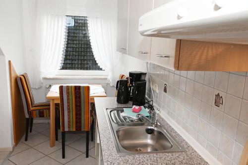 uma cozinha com um lavatório e uma mesa com uma janela em Bernstein Mare-Comfort Wohnung 7 em Büsum