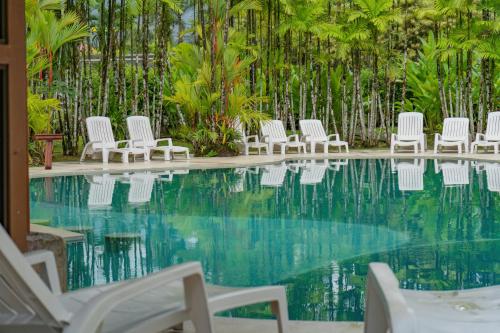 a group of white chairs by a swimming pool at Arenal Secret Gardens in Fortuna
