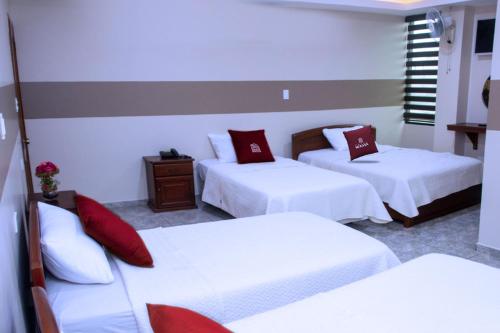 a hotel room with three beds with red pillows at Hotel MiKasa in Oliva