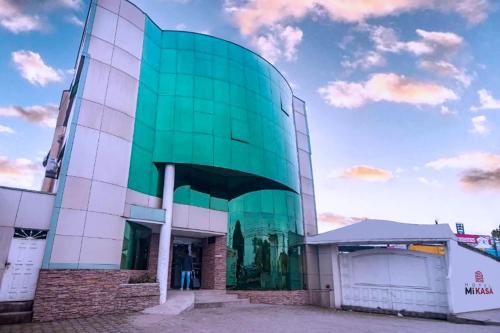 a green glass building with a sky in the background at Hotel MiKasa in Oliva
