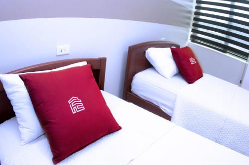 two beds in a room with red and white pillows at Hotel MiKasa in Oliva