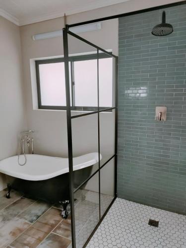 a bathroom with a tub and a glass shower at Oppi Plaas See Uitsig 3 in Glentana