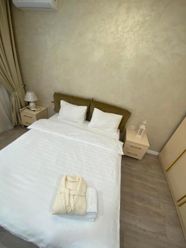 ein Schlafzimmer mit einem weißen Bett und einer Handtasche darauf in der Unterkunft Уникальная квартира в жк Амир in Almaty