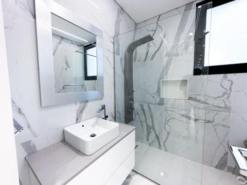 a white bathroom with a sink and a mirror at Villa Montana in São Vicente