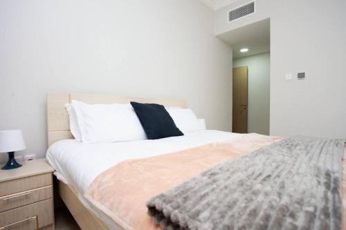 a bedroom with a large white bed with a blanket on it at Luxury waterview 2BD in Sharjah