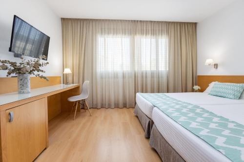 アリカンテにあるダニヤ アリカンテのベッド、デスク、テレビが備わるホテルルームです。