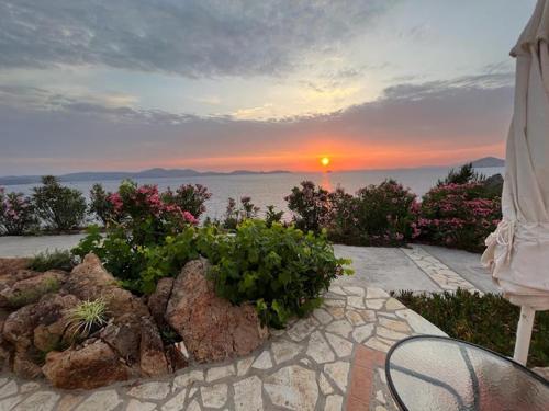 a view of the sunset from a patio with rocks and plants at Patmos Garden Sea in Grikos