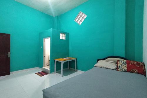 a bedroom with blue walls and a bed and a table at Wisma Hiro Pertiwi in Palembang