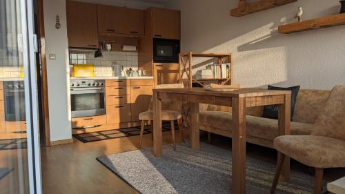 a living room with a wooden table and a kitchen at Ferienbungalow Kajüte in Ostseebad Koserow
