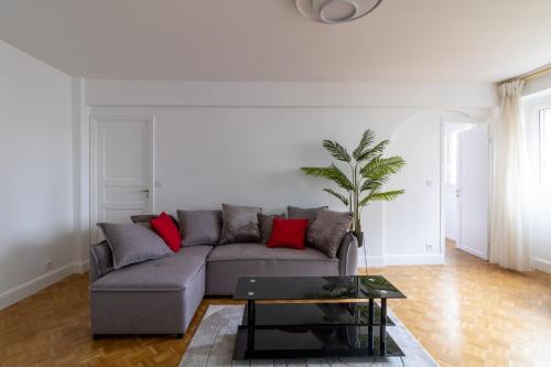 - un salon avec un canapé gris et des oreillers rouges dans l'établissement Comfortable apartment with view - Welkeys, à Puteaux