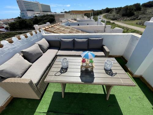 una mesa de patio con una sombrilla en la azotea en Apartamento 308 Castell Sol CB, en Es Mercadal