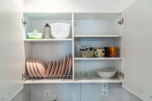 une armoire blanche remplie de bols et d'autres ustensiles de cuisine dans l'établissement Syntagma square, 55sqm Golden Suite, à Athènes