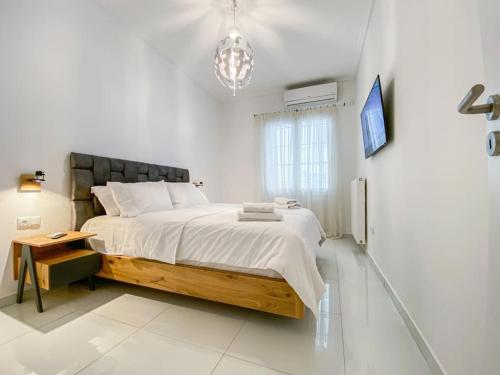 - une chambre blanche avec un grand lit et un lustre dans l'établissement Syntagma square, 55sqm Golden Suite, à Athènes