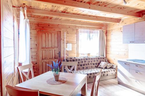 ein Wohnzimmer mit einem Tisch und einem Sofa in der Unterkunft Domki Morena - Rodzinne Domki Blisko Plaży in Karwia