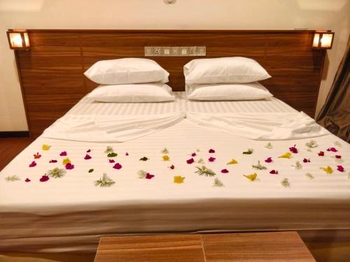 un letto con fiori e due cuscini di Akiri Grand a Thinadhoo