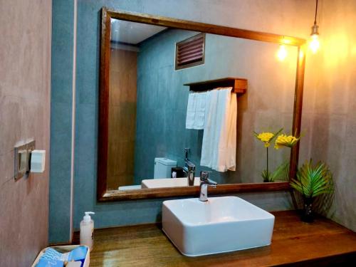 uma casa de banho com um lavatório e um espelho grande em Akiri Grand em Thinadhoo