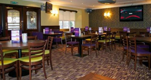 a restaurant with tables and chairs and a tv at OYO Lochway Hotel in Dumbarton