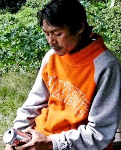 a man sitting in the grass holding a camera at Joben Evergreen Camp Centre in Tetebatu