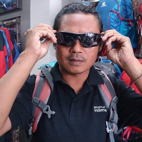 a man is adjusting his sunglasses in a store at Joben Evergreen Camp Centre in Tetebatu