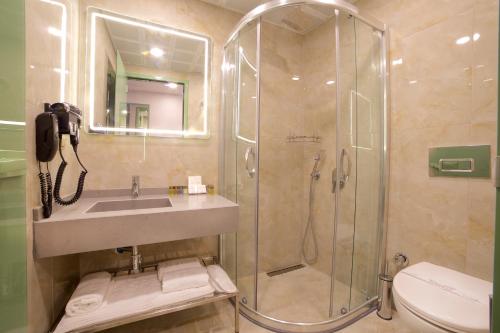een badkamer met een douche, een wastafel en een toilet bij Çanakkale Bosphorus Port Aspen Hotel in Canakkale