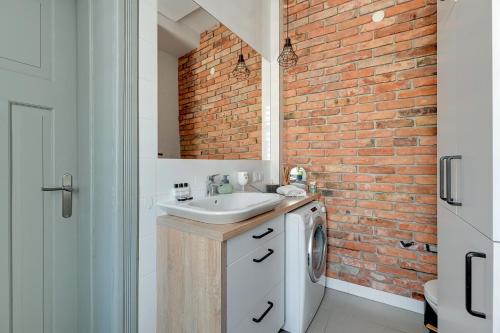 een badkamer met een wastafel en een bakstenen muur bij Dom & House - Apartment Sea Of Mint in Sopot