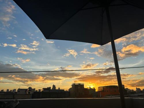 a view of a sunset from a balcony with an umbrella at Stargazing tent in Balcony at EKG House Rental in Manila