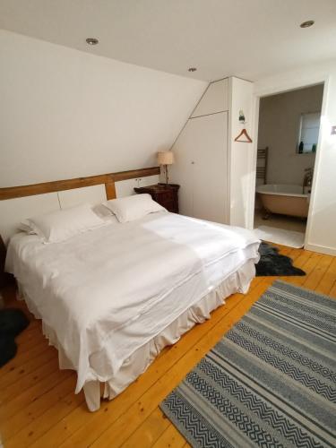 een slaapkamer met een groot wit bed en een tapijt bij Prestwick Oak - 3 King Bed Ensuite Quirky Contemporary in Chiddingfold