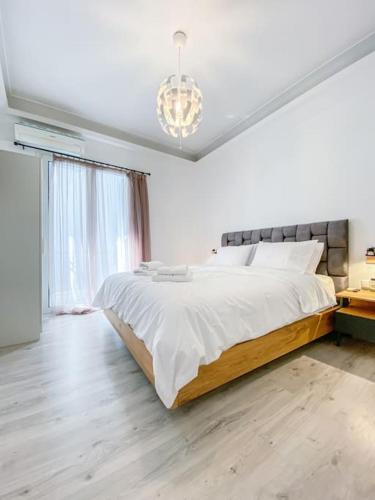 a white bedroom with a large bed with a chandelier at Syntagma square, 60sqm Platinum suite in Athens