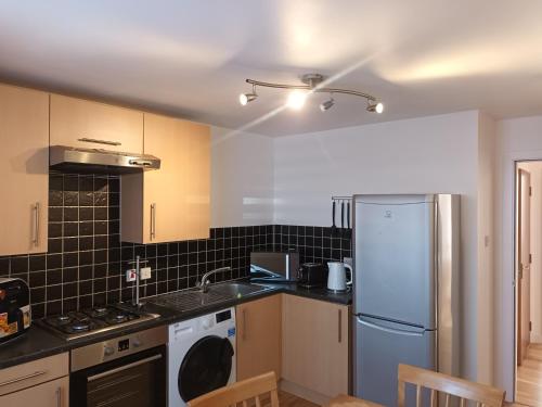 uma cozinha com um frigorífico branco e um lavatório em Spacious Elegant 2-BR Apartment in Aberdeen City Centre em Aberdeen