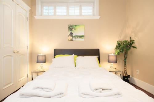1 dormitorio con 1 cama blanca grande y 2 lámparas en Oakridge Luxury Homestay en Vancouver