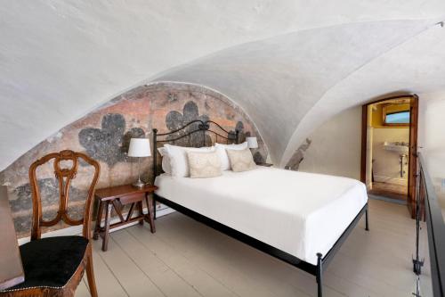 - une chambre avec un lit blanc et une chaise dans l'établissement Numa Florence Santo Spirito I Apartments, à Florence