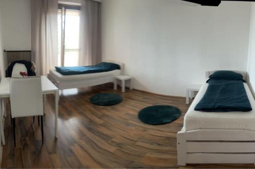 Pokój z 2 łóżkami, stołem i biurkiem w obiekcie Ruhige Wohnung in Schwechat nähe Flughafen w mieście Schwechat