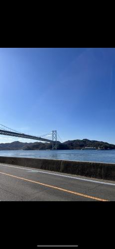 a road with a bridge in the middle of the ocean at しまの宿 Island Country Inn in Onomichi