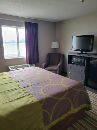 une chambre d'hôtel avec un lit, une télévision et une chaise dans l'établissement Super 8 by Wyndham Aurora/Naperville Area, à Aurora