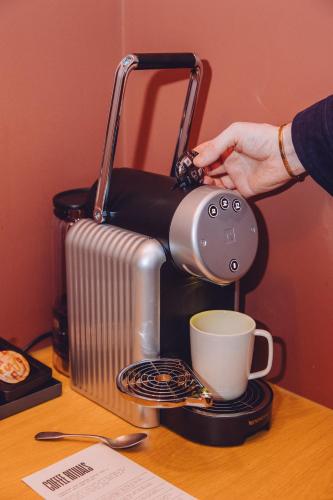 a person is making a cup of coffee on a table at TRIBE London Canary Wharf in London