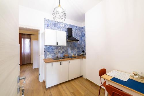 a kitchen with white cabinets and blue tiles on the wall at Dimora Don Antonio in Pontecagnano
