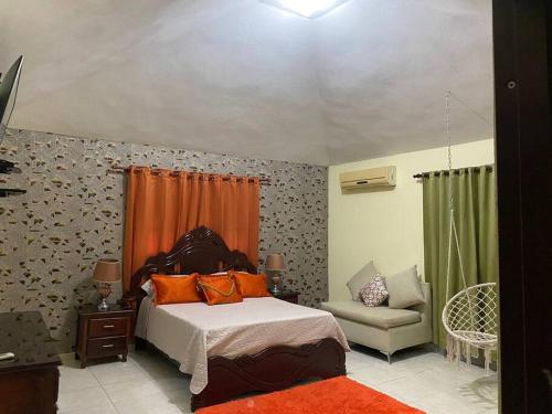 a bedroom with a bed with orange pillows and a chair at Apartamento acogedor Para una estancia Feliz! in Mendoza