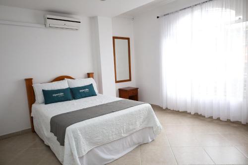 um quarto branco com uma cama com almofadas azuis em Ayenda Torre 2 em Apartadó