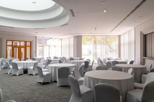 a room with white tables and chairs and windows at eStay Hotel in Dubai